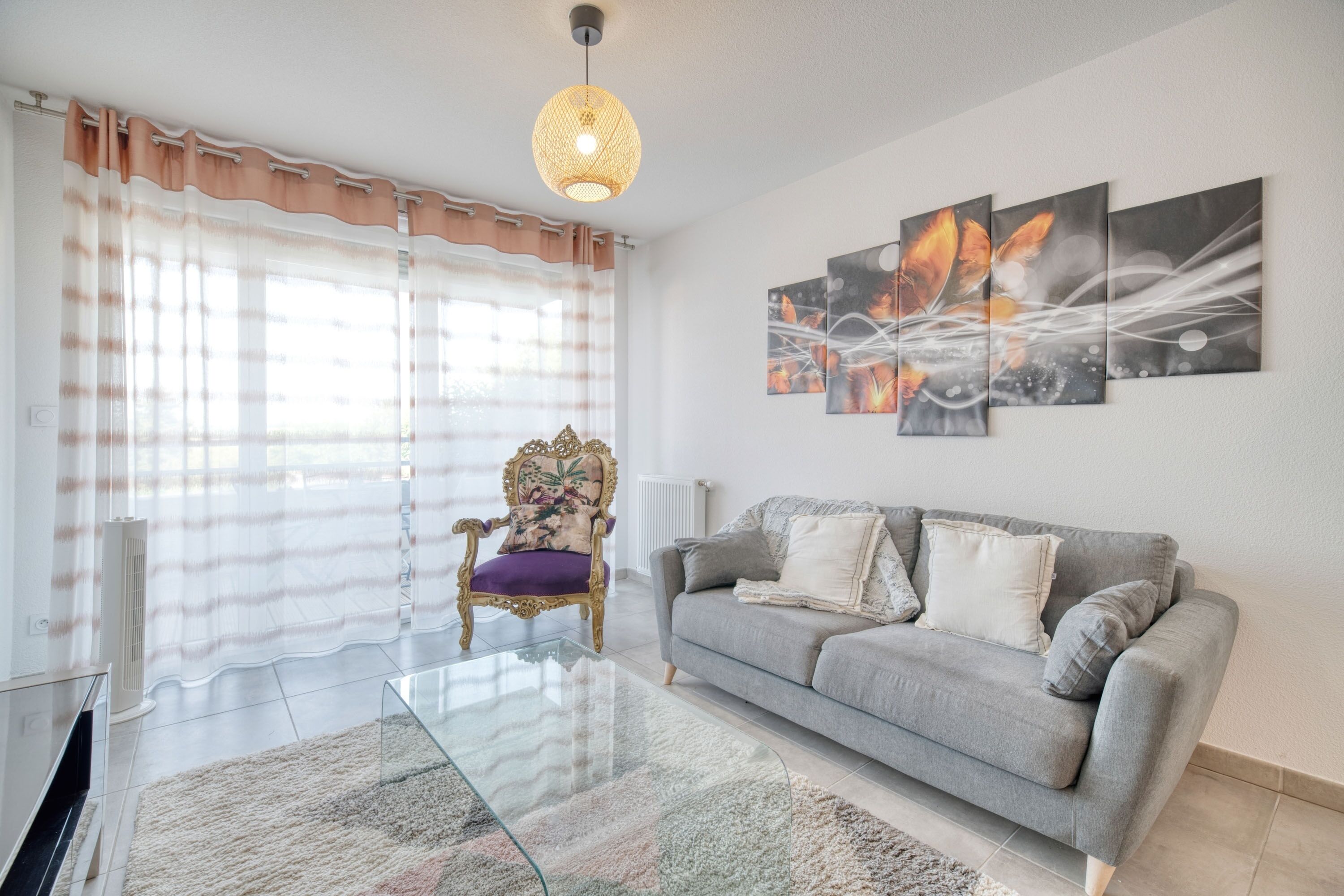 A modern living room with a grey sofa, a glass coffee table, and a decorative chair.