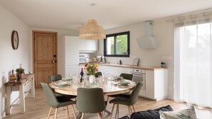 Eine moderne Küche mit weißen Schränken, einem Holztisch und grünen Stühlen.