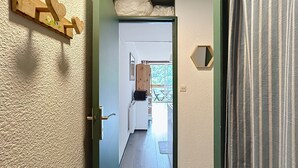 Un couloir orné d’un décor mural en bois, avec une porte et une vue sur une pièce dotée d’une fenêtre et d’une porte en bois.