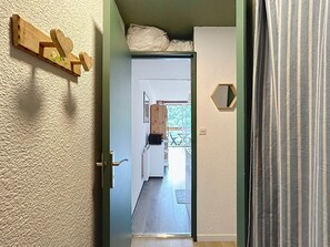 A hallway with a wooden wall decoration, a door, and a view into a room with a window and a wooden door. - Le Korrigan - Vue Montagne (Villarembert)