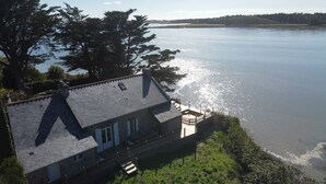 Une maison avec un toit en pente, un balcon et une vue sur une vaste étendue d’eau.