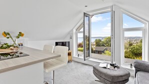 Eine moderne Küche mit Essbereich, großen Fenstern und Blick ins Freie.
