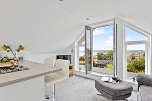 Ein modernes Wohnzimmer mit Essbereich, großen Fenstern und Blick auf die Landschaft.