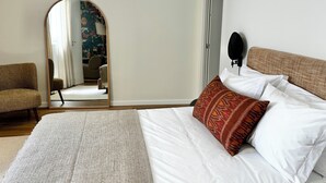 Une chambre à coucher avec un grand lit, une chaise, un miroir et une porte.