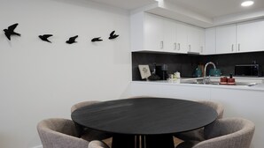 A modern kitchen with white cabinets, a black countertop, and a round dining table with four chairs. - Storyteller's Retreat. Design and comfort in the historic center of Ponta Delgada! (Ponta Delgada)
