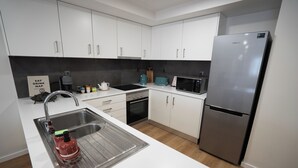 A modern kitchen with white cabinets, stainless steel appliances, and a built-in dishwasher. - Storyteller's Retreat. Design and comfort in the historic center of Ponta Delgada! (Ponta Delgada)