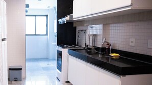 A modern kitchen with white cabinets, a black countertop, and a stainless steel range hood.
