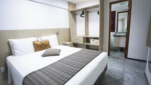 A hotel room with a bed, a bedside table, a wardrobe, and a mirror.