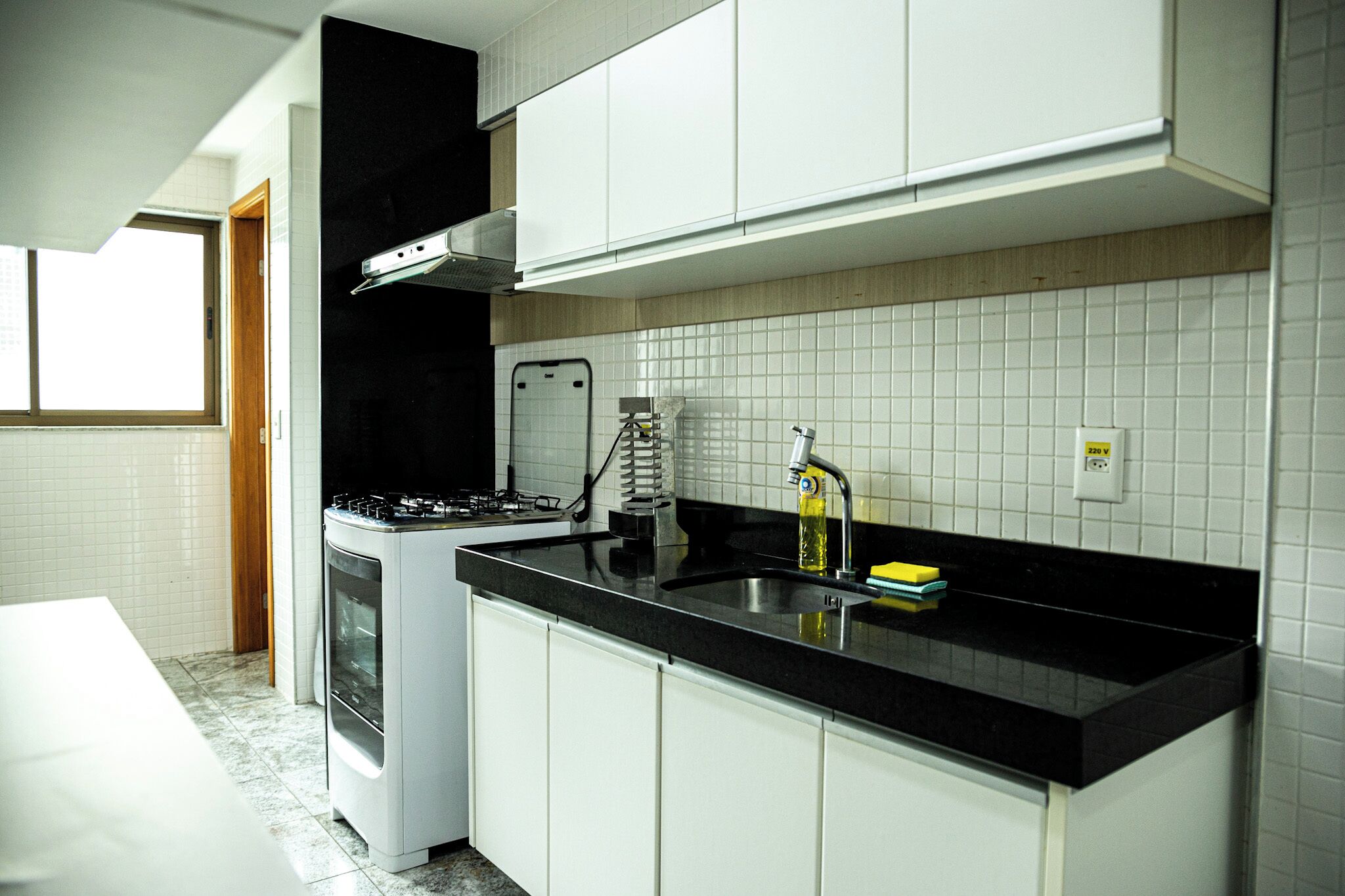 A modern kitchen with white cabinets, a black countertop, and a built-in stove.