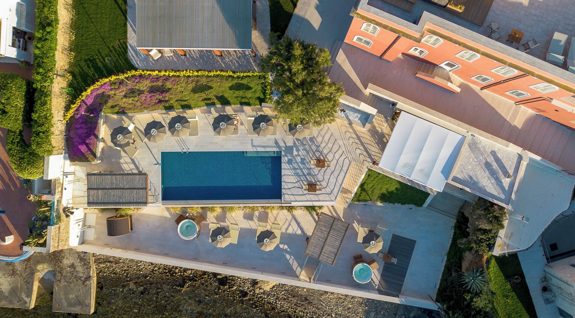 An aerial view of a property with a swimming pool, outdoor seating, and a garden.