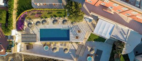 An aerial view of a property with a swimming pool, outdoor seating, and a garden.