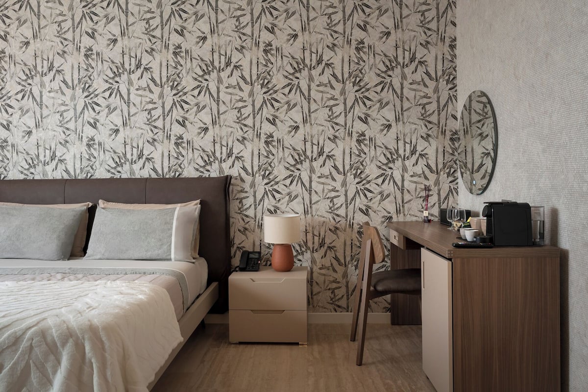 Un dormitorio con cama, mesita de noche, lámpara y escritorio con silla.
