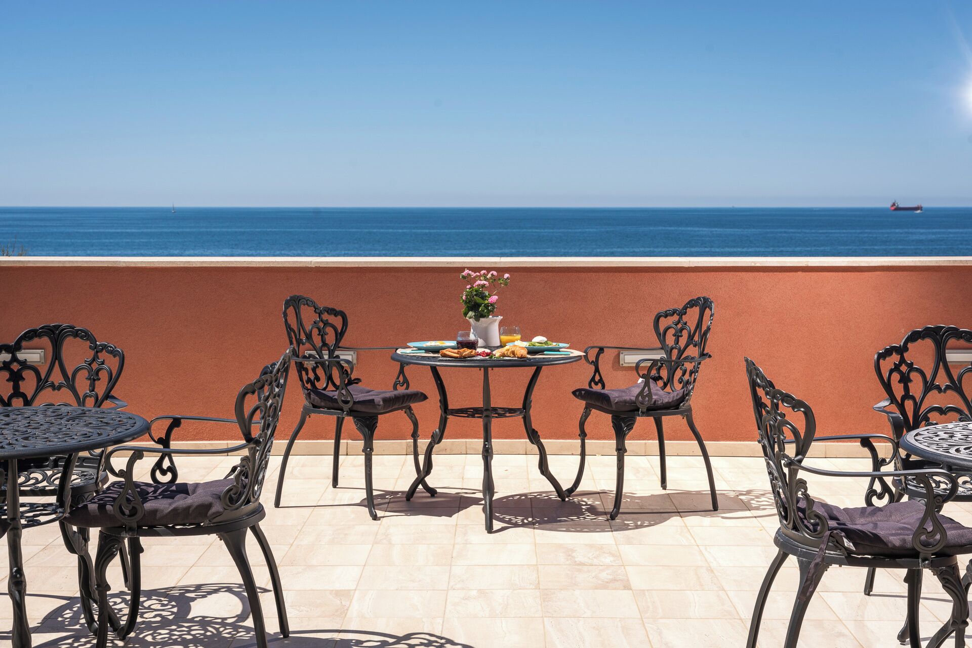 A terrace with outdoor seating and a view of the sea.