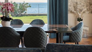 Un espace repas avec vue sur l’océan, comprenant une table, des chaises et un luminaire suspendu.