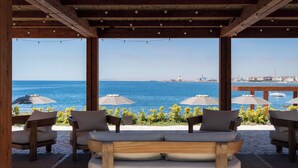 A covered outdoor seating area with a view of the sea, wooden furniture, and string lights. - Villa Giada Luxury Boutique (Civitavecchia)