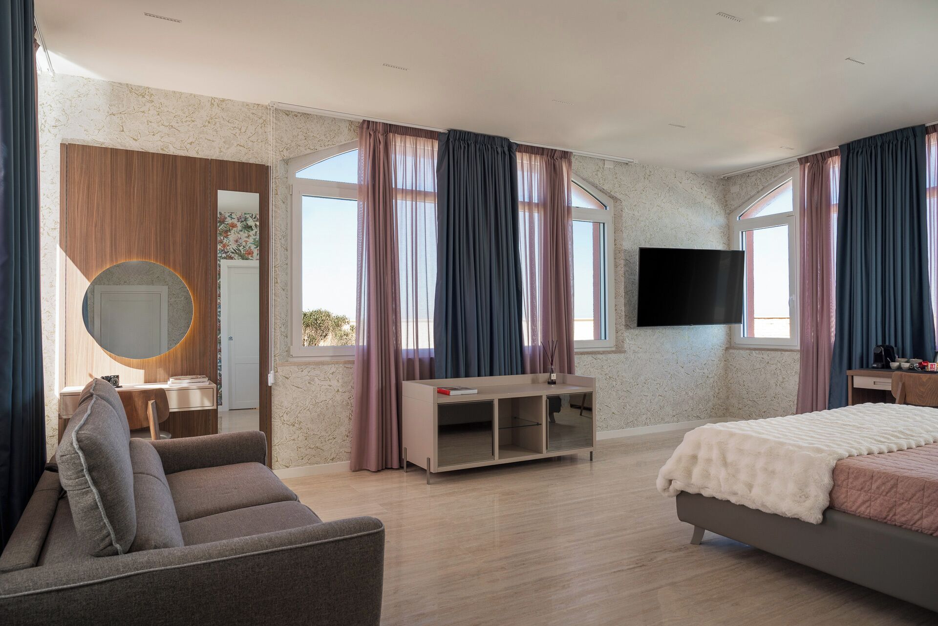 Un dormitorio con cama, televisor, escritorio y silla.