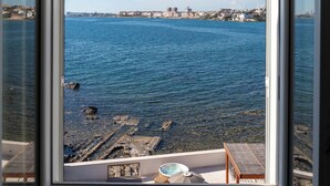 A view through a window with a clear blue sky, a body of water, and a distant cityscape. - Villa Giada Luxury Boutique (Civitavecchia)