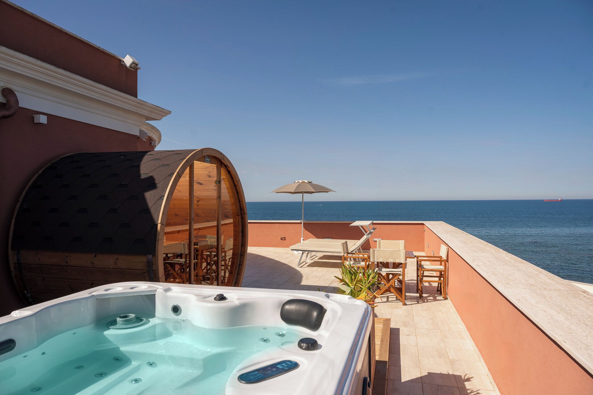 Un jacuzzi en un balcón con vista al mar y una estructura de madera.