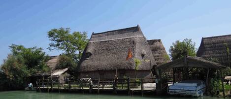 A traditional thatched-roof house by a calm river.