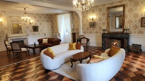 A traditional living room with a fireplace, ornate wallpaper, and classic furniture. - Château de la Rochetière (Marcilloles)