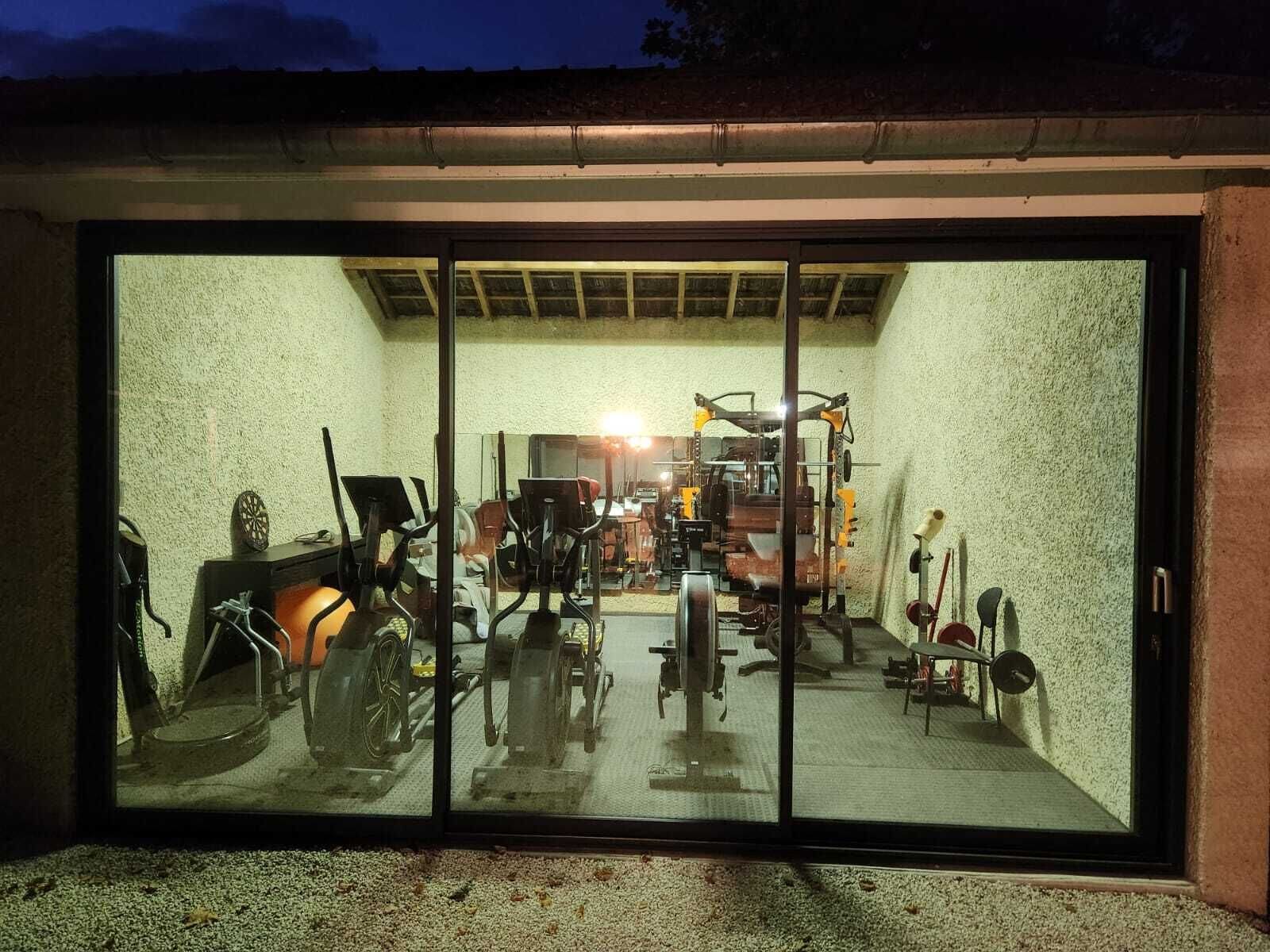 A gym with exercise equipment, including treadmills and weights, visible through a glass door.