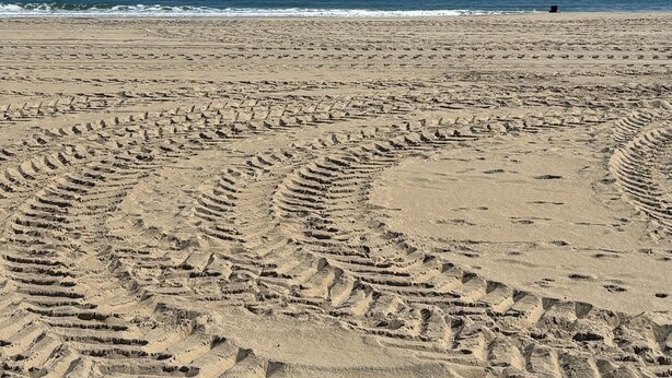 A sandy beach with footprints leading to the water. - White Marlin & Concerts | 2BR w/ Pool & Parking (Ocean City)