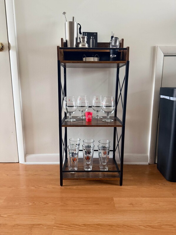 A wooden shelf with three tiers holding glasses and a red cup. - White Marlin & Concerts | 2BR w/ Pool & Parking (Ocean City)