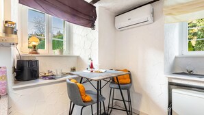 A kitchen with a table and chairs, an air conditioner, and a window with curtains. - Apartment Schlossmühle in Bigge-Olsberg (Olsberg)