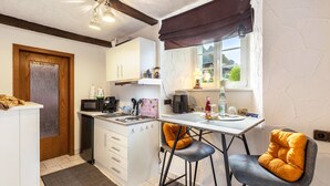 A compact kitchen with white cabinets, a microwave, a coffee maker, and a window with a view of greenery. - Apartment Schlossmühle in Bigge-Olsberg (Olsberg)