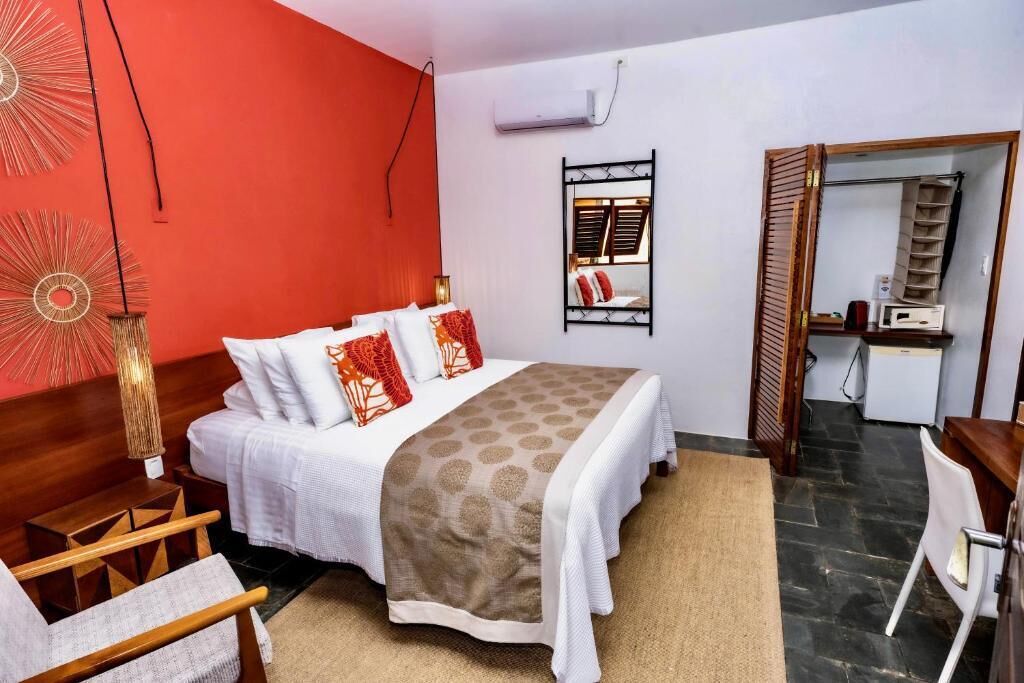 A hotel room with a bed, a desk, a chair, a wardrobe, and a mirror.
