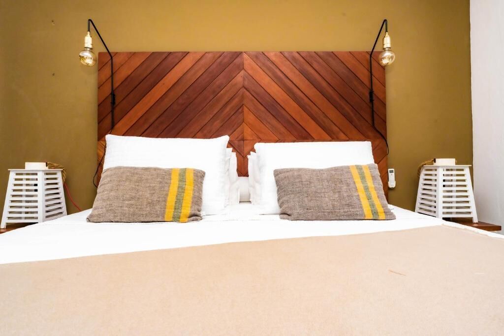 A bed with a wooden headboard, two bedside tables, and two lamps.