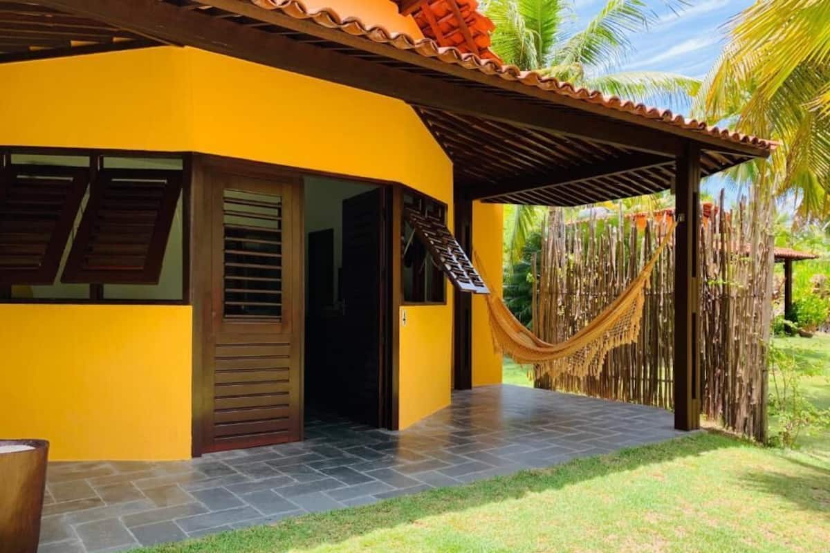 A yellow building with a covered patio and a hammock.