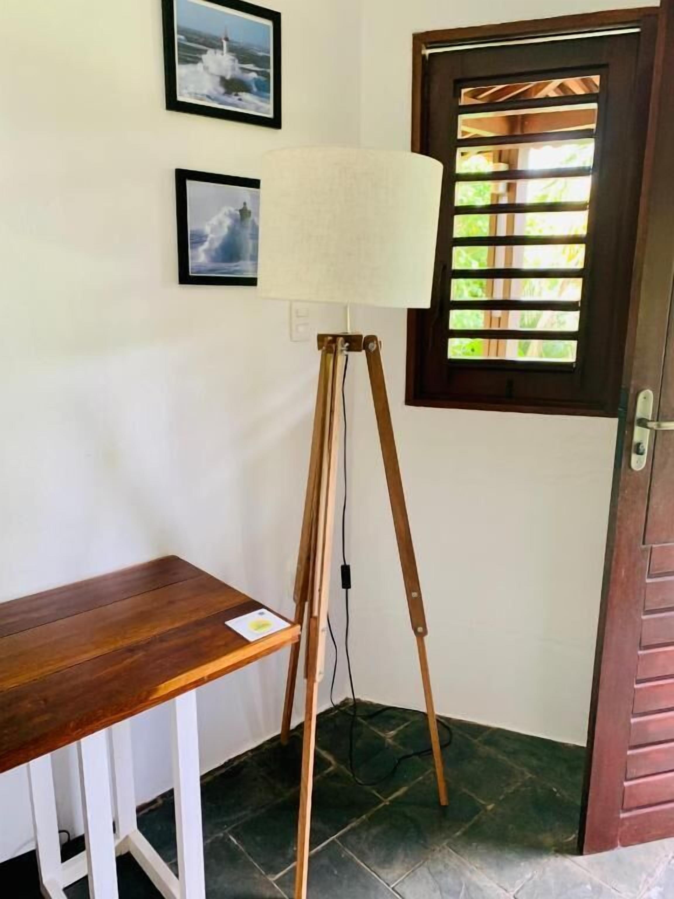 Una habitación con un escritorio de madera, una lámpara de pie y una puerta con ventana.