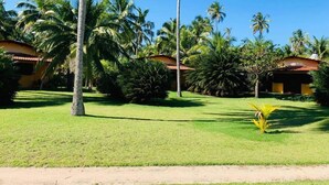 A tropical resort with palm trees, a well-maintained lawn, and traditional-style buildings with red-tiled roofs. - Côté Sud Pousada de Charme (São Miguel dos Milagres)