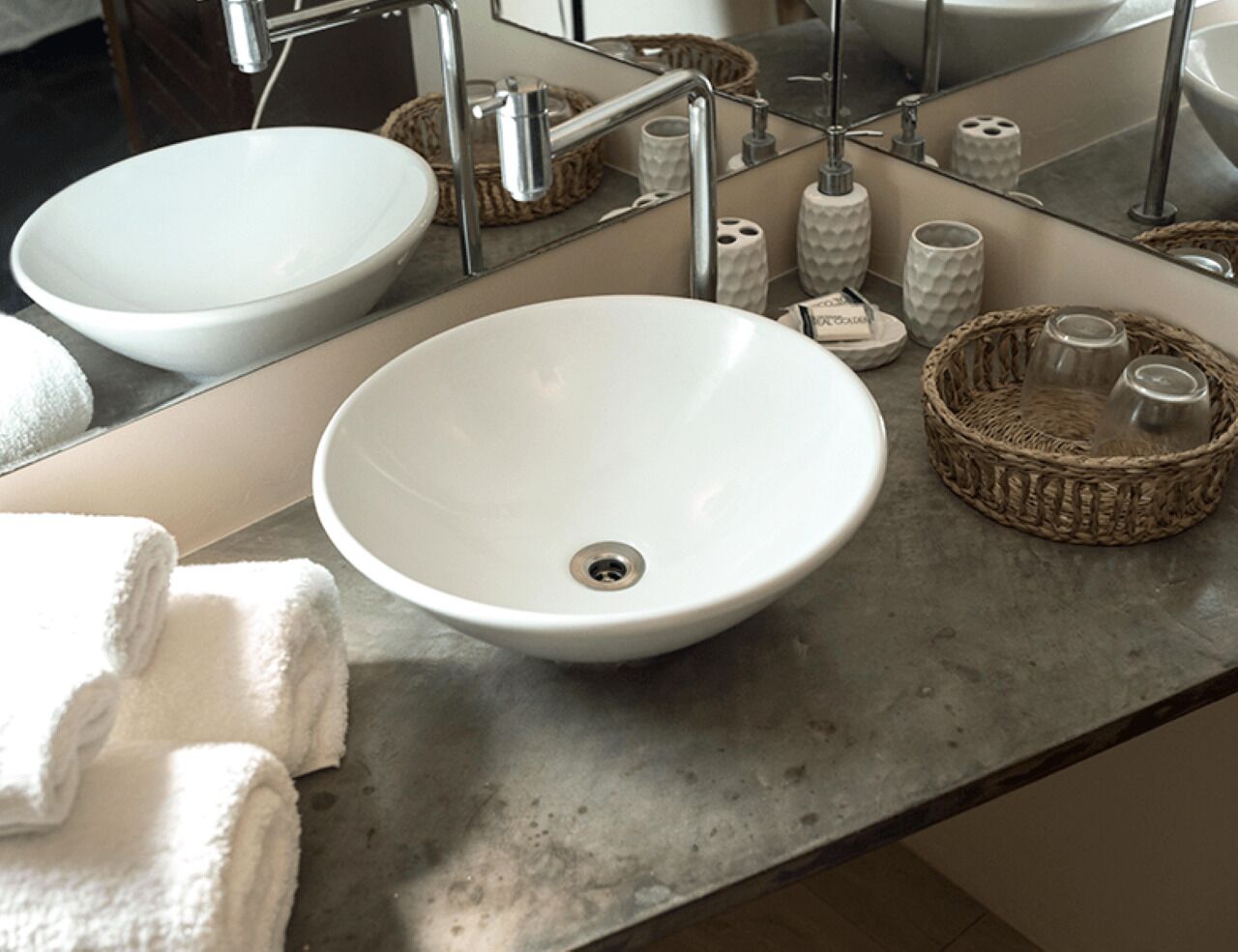 Un baño con un lavamanos blanco, un espejo y un perchero para toallas.