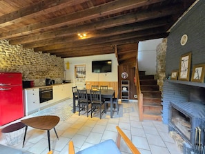 A cozy kitchen with a stone wall, a red refrigerator, and a dining area with a wooden table and chairs.