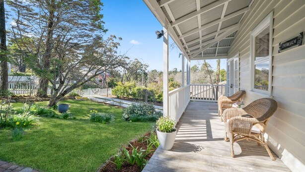A covered porch with wicker furniture, a well-maintained lawn, and a white picket fence. - Inchcolm – Your Quintessential Blue Mountains Getaway (Leura)