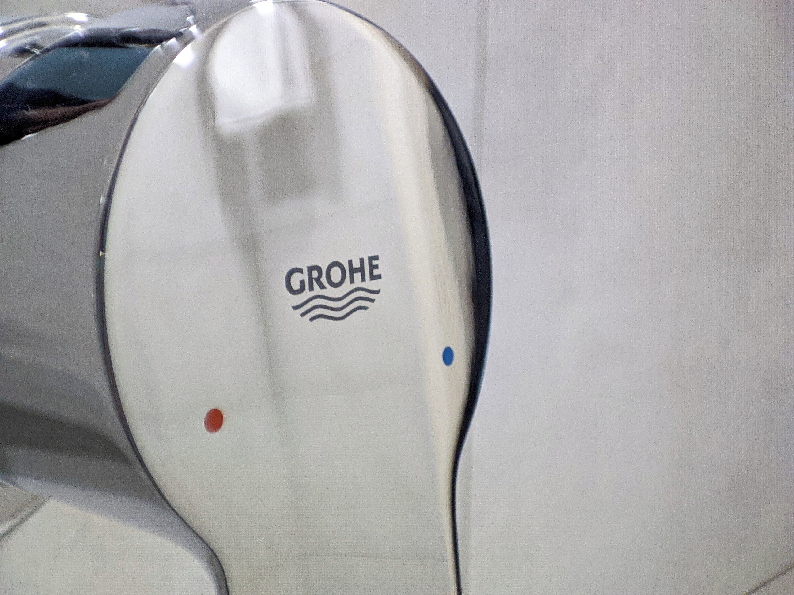 A metallic surface with the GROHE logo and two colored dots.