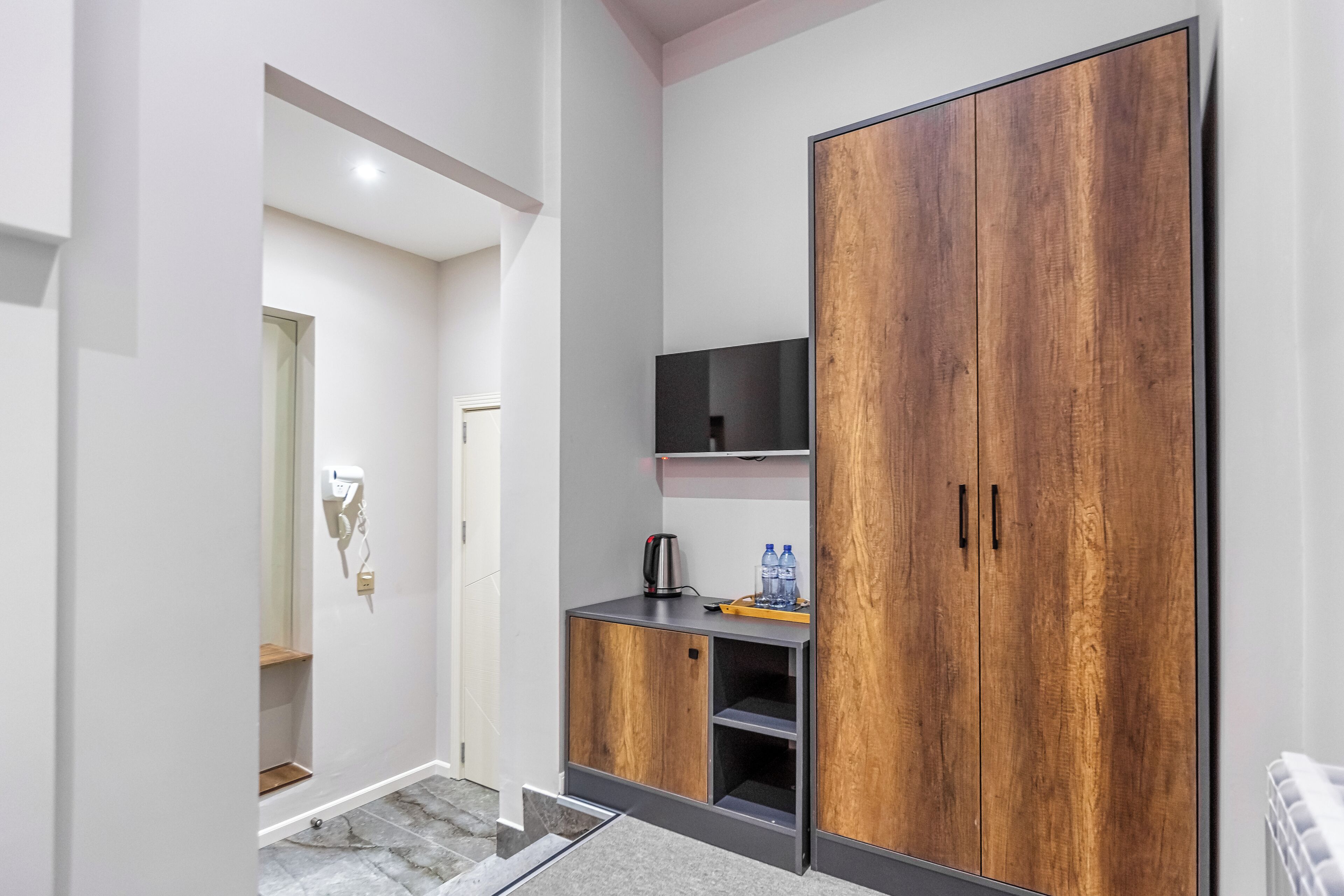 A modern bathroom with a shower, a vanity with a mirror, and a large wardrobe.