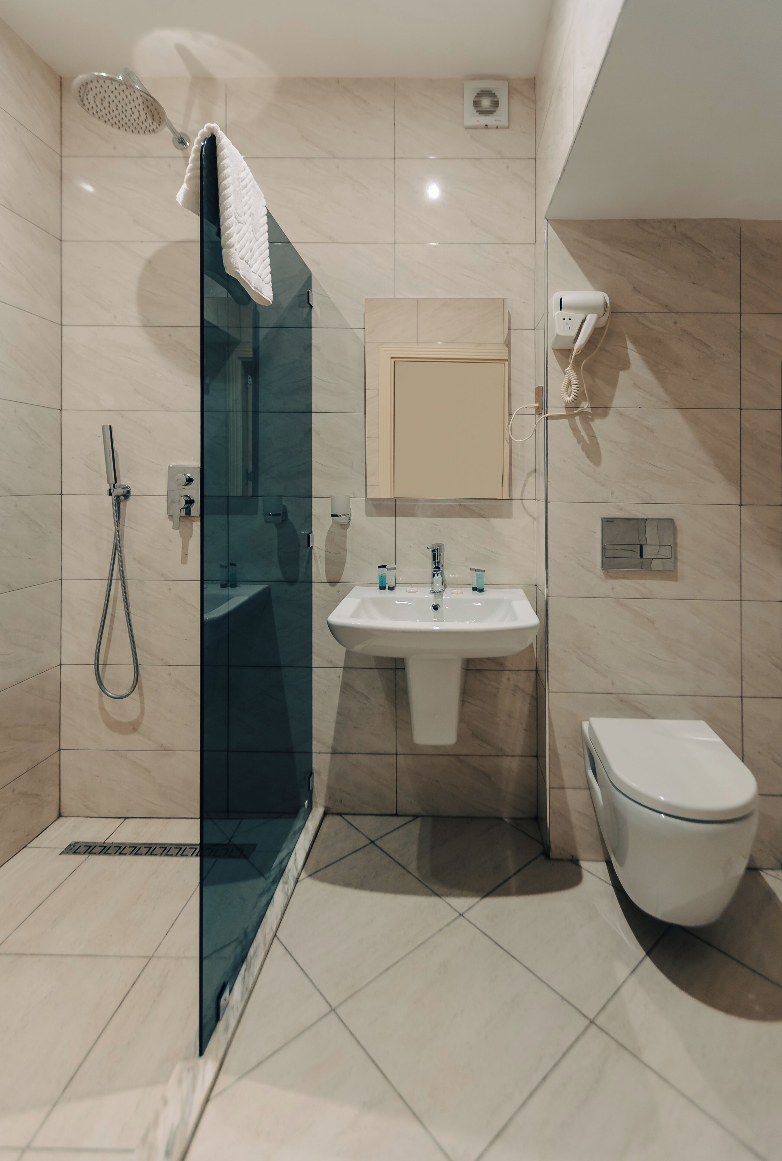 A modern bathroom with a glass-enclosed shower, a white sink, and a toilet.