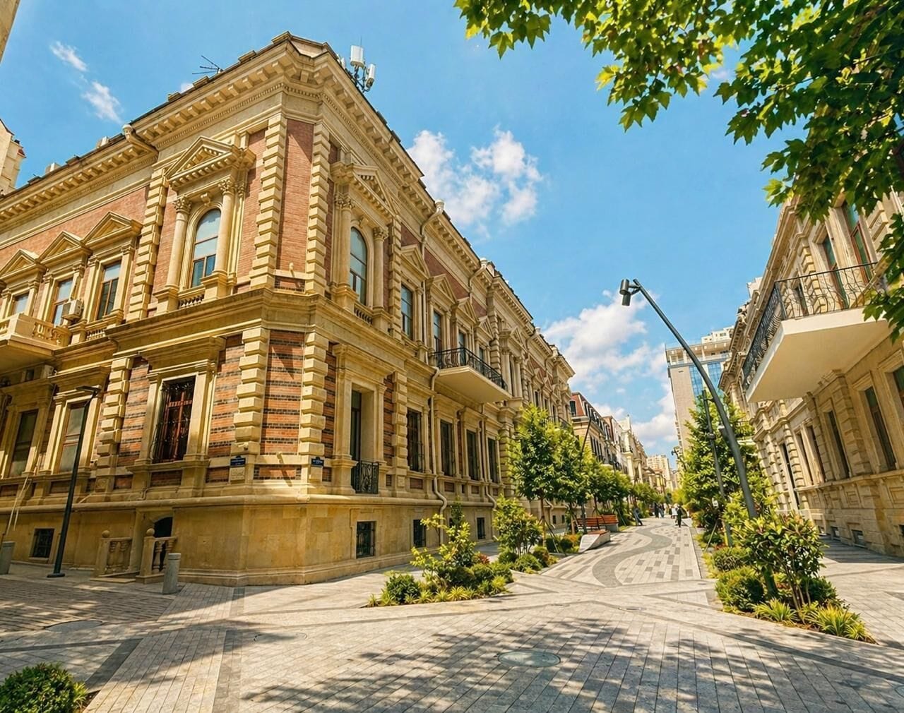 Un bâtiment historique à l’architecture classique, une rue pavée et des arbres.