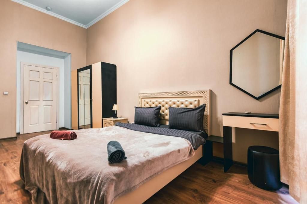 A bedroom with a bed, a desk, a mirror, and a wardrobe.