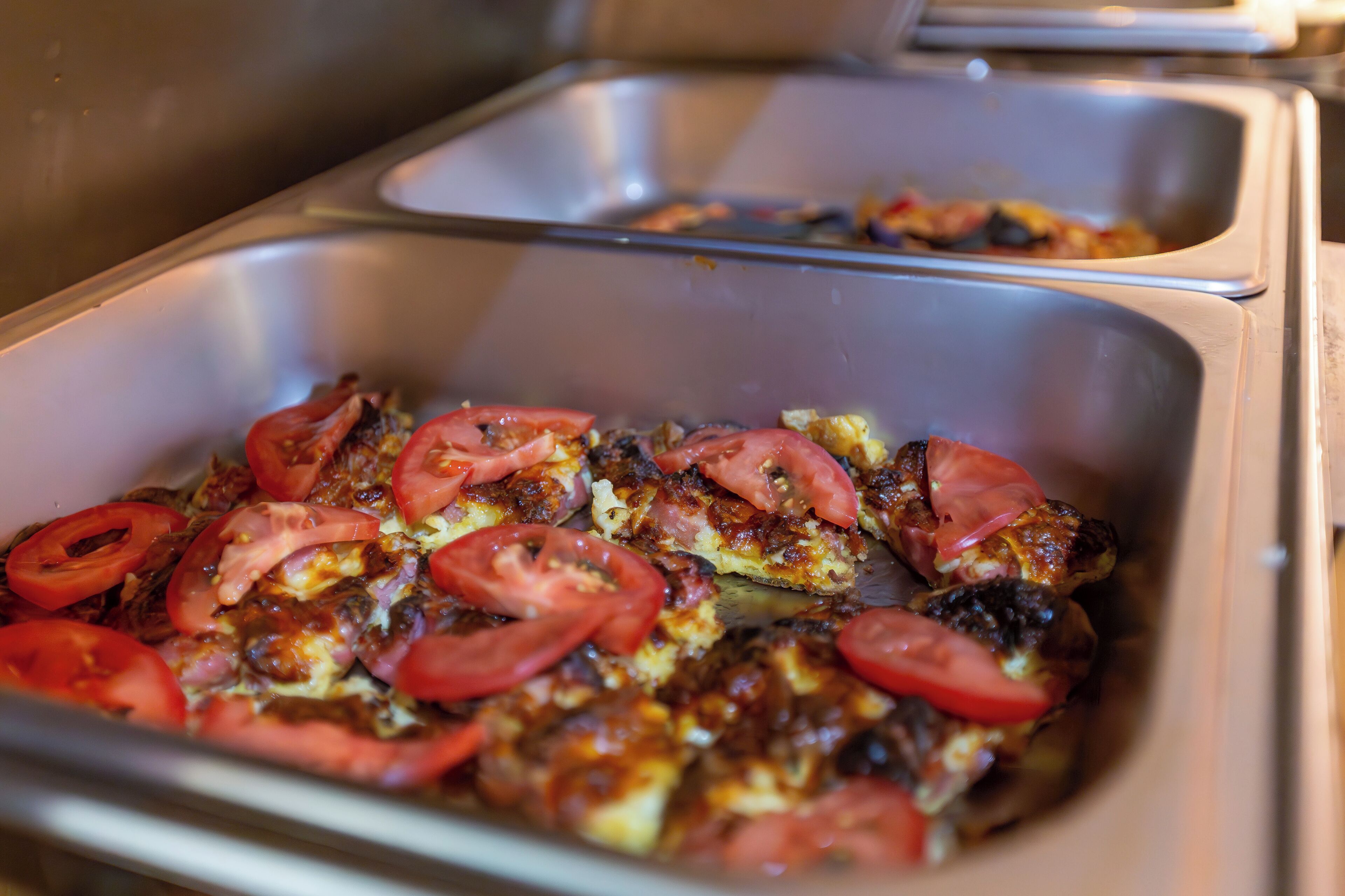 Un buffet proposant une variété de plats, dont un plat cuit au four, garni de tomates.