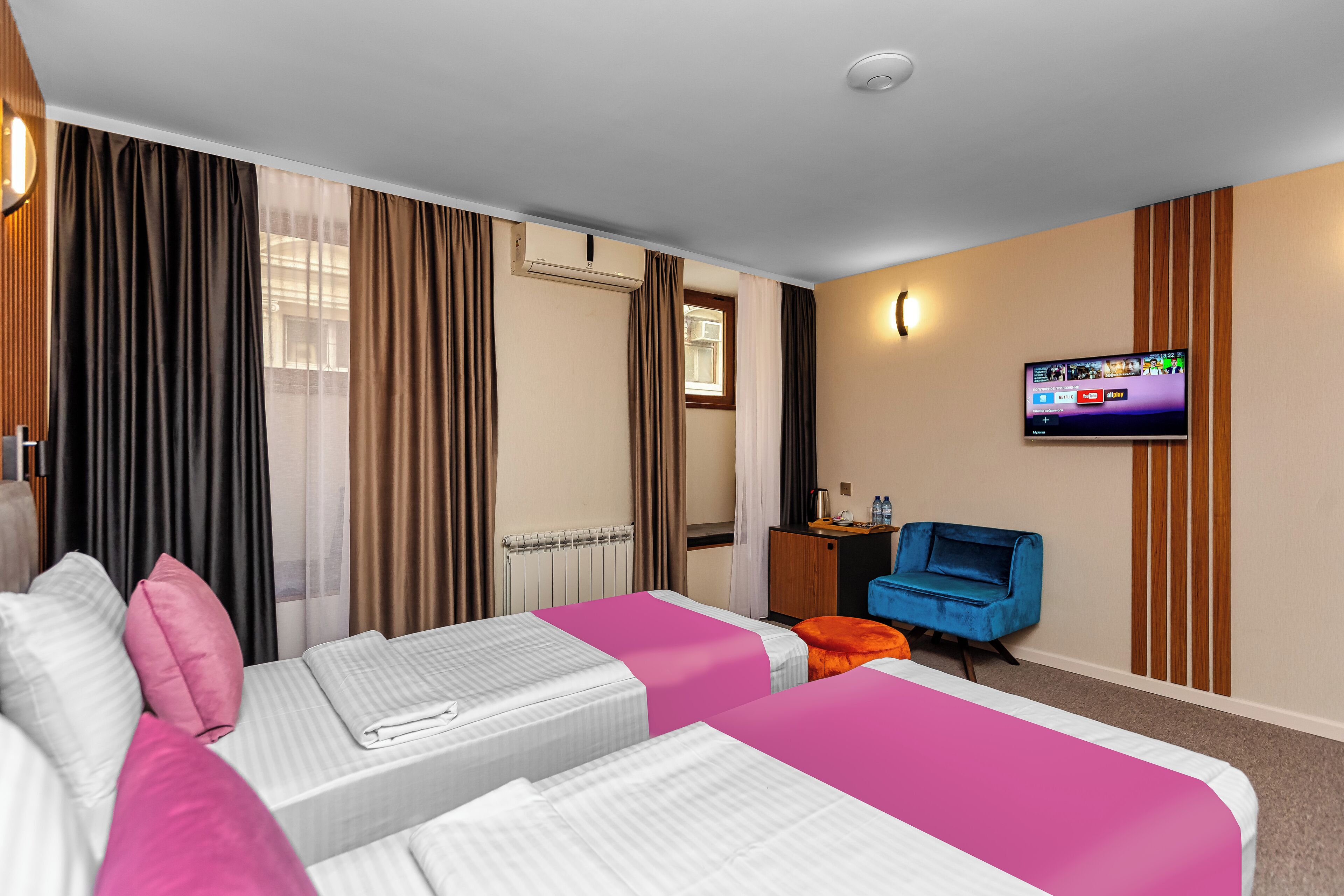 A hotel room with two beds, a TV, a desk, and a chair.