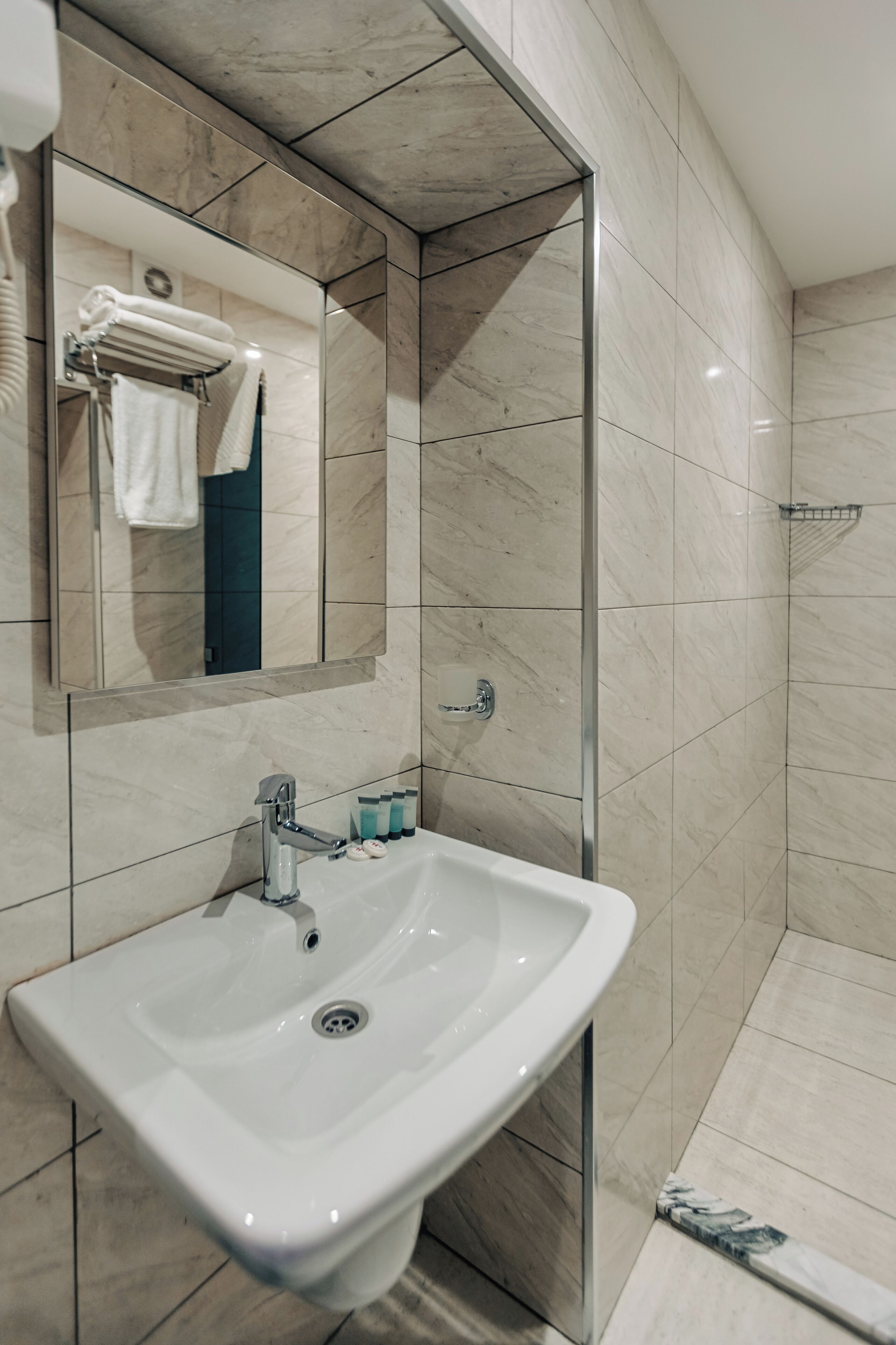 A modern bathroom with a white sink, a mirror, and a glass shower enclosure.
