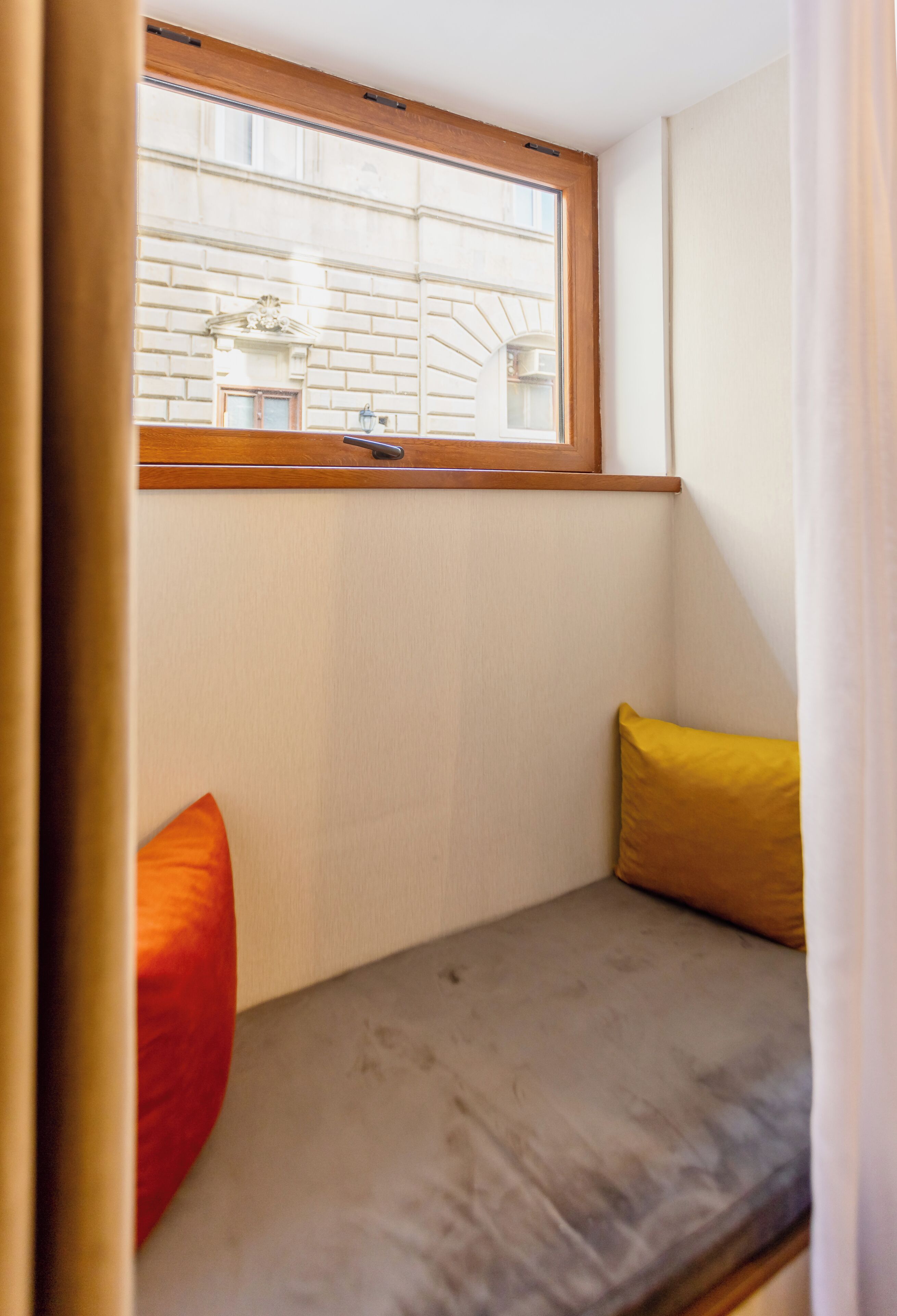 A small, enclosed room with a window, a bench, and two cushions.
