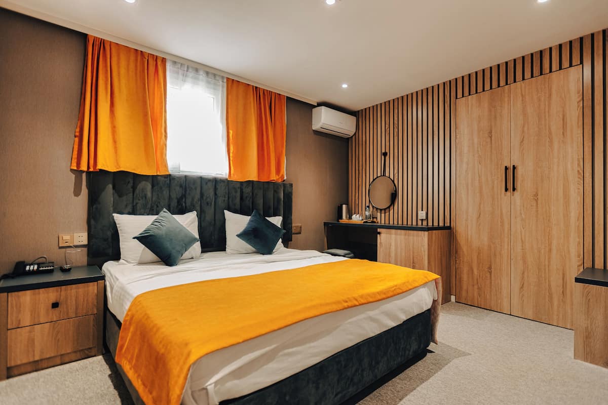 A bedroom with a bed, bedside tables, a desk, a mirror, and a wardrobe.