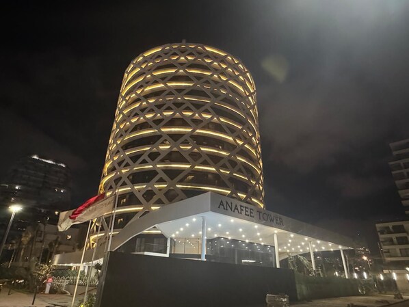 A modern tower with a distinctive circular design and a sign reading "ANAFEI TOWER".