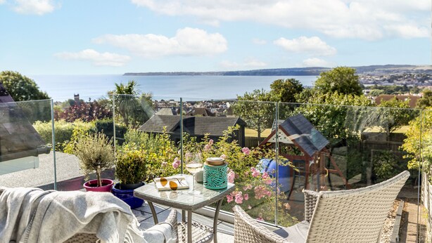 A balcony with a table, chairs, and potted plants. - Swanston Lodge in Paignton (Paignton)