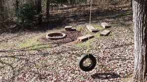 A playground with tire swings and stepping stones in a wooded area.